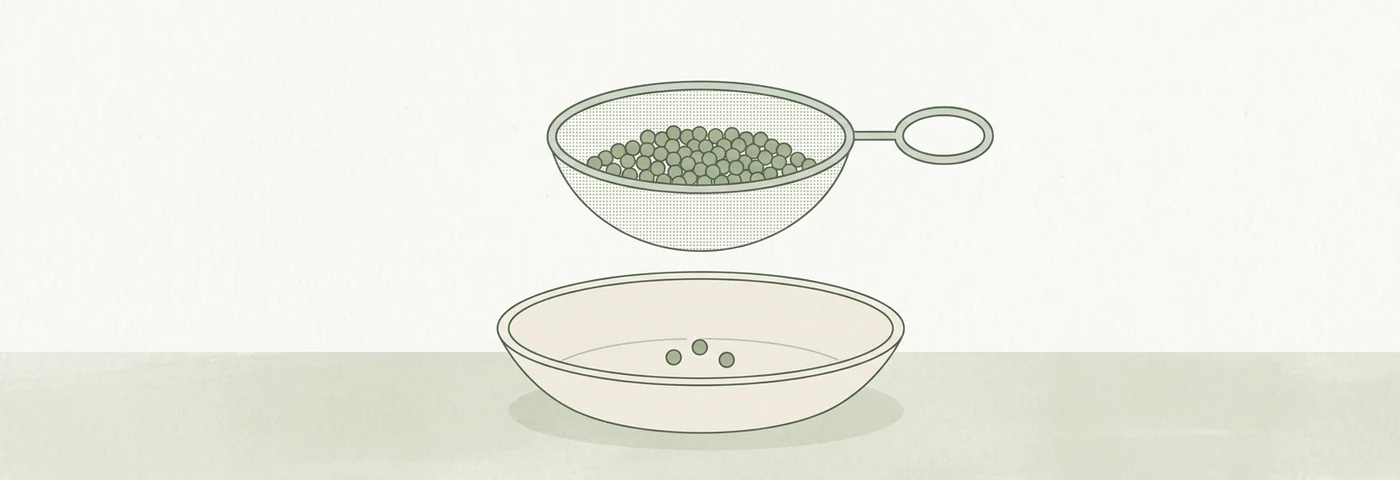 Ilustracja: sitko pełne drobnych ziaren uniesione nad miską, w której leżą tylko trzy ziarna